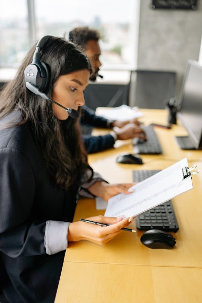 Focused customer support agents working with headsets and documents in an office setting.